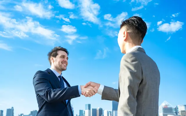 笑顔の外国人ビジネスマン男性と握手する日本人ビジネスマン男性